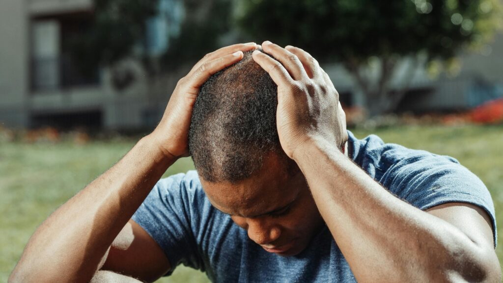 Young adult holding their head in distress, showing signs of anxiety, mental stress, and emotional overload commonly experienced in anxiety disorders.